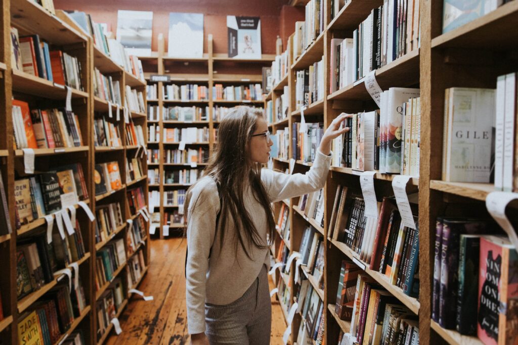 Eine Frau sieht sich Female Leadership Bücher in einer Bibliothek an.