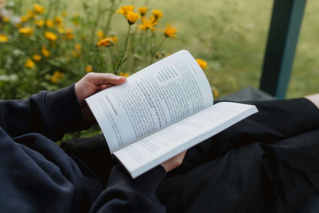 a person reads a book in nature for self-care